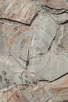 Bumpy stone surface. Stone background. A fragment of an old wall with the shadow of a plant on it.