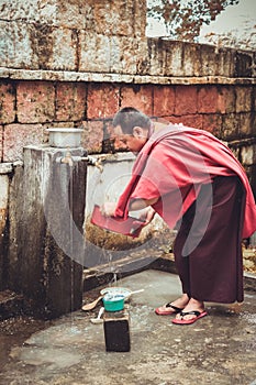 Bumthang, Bhutan - September 14, 2016: Monk washing dishes near Kurjey Lhakhang (Temple of Imprints) in Bumthang valley, Bhutan