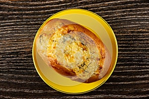 Bun with cheese and garlic in saucer on wooden table. Top view