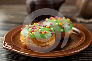 Bun, donut covered with glaze. Tutti frutti bun on a plate. Sweet pastries. Dessert. Still life. Close-up