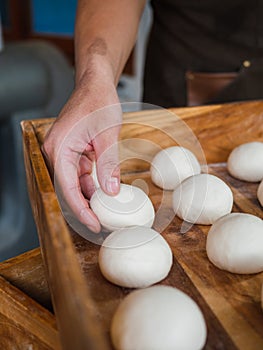 Bun doughs in wooden tray with hand