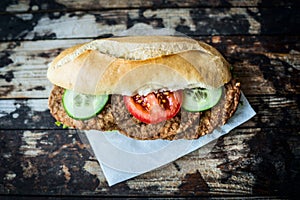 Bun with meat cutlets with cucumber and tomatoes on a wooden background, top view, toning