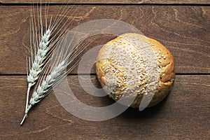 Bun of white bread and ears of corn lying on old wooden table