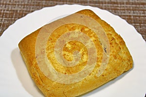 Bun on a white plate on the table.