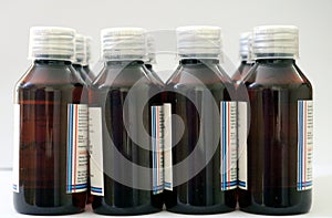 Bunch of amber colored medicine pet bottles with transparent 10 ml dosage cap used in pharma sector as cough syrup
