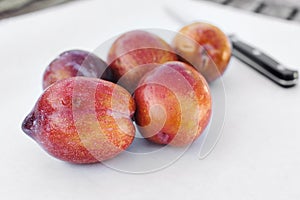 A Bunch of Amigo Pluot Fruit with a Knife in View on White Paper
