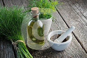 Bunch of aromatic fresh green dill, mortar of fennel seeds and dill oil bottle.