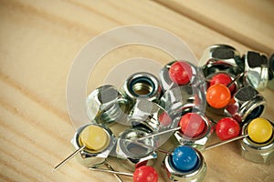 Bunch of arranged pins with vivid colorful pinheads and industrial metal nuts screws