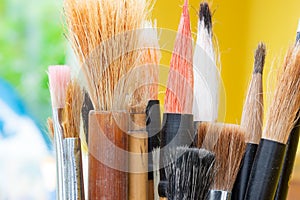 Bunch of artists paintbrushes. Green and yellow background.