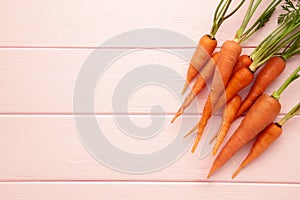 Bunch of baby carrots on pink background. Space for text