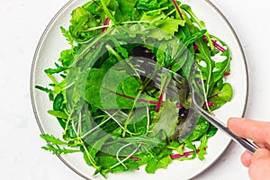 Bunch of baby green leaves on the plate top view. Arugula, spinach, beet, lettuce salad foliage close up.