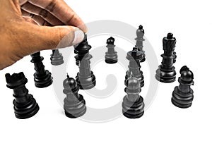 Bunch of black colored chess pawns placed over a white background while one person sorting them