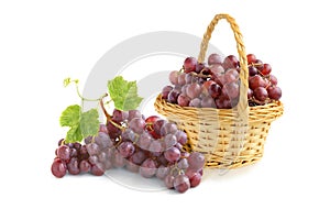 Bunch of black grapes and grapes in a wicker basket isolated on white