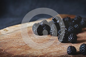 A bunch of blackberries on the cutting board with black background behind