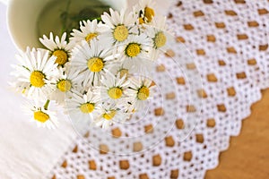 Bunch of blooming daisies on rustic wooden background with a doily
