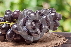 Bunch of blue grapes on a wooden table with blurred background
