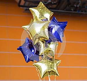 Bunch of Blue and Yellow Mylar Balloons with orange wall photo