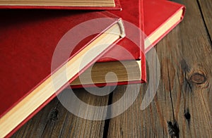 A bunch of books with a scarlet cover on a wooden table. Red books are thrown on the table. books with a red cover lie