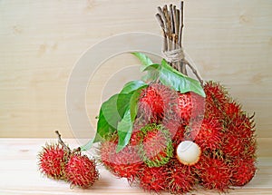 Bunch of Bright Color Red and Green Fresh Ripe Rambutan Whole Fruits and Peeled Isolated on Wooden Table