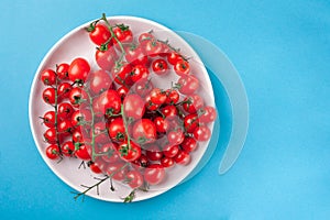 Bunch of bright fresh red cherry tomatoes on round plate