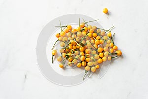 A bunch of bright yellow aji charapita peppers from the garden scattered on a white marble background with copy space