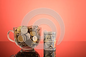 Bunch of coins and money banknote on the table over red background