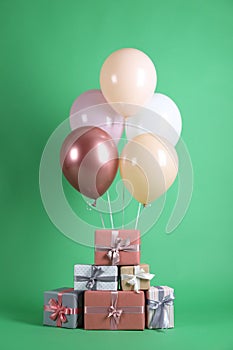 Bunch of color balloons and beautifully wrapped gift boxes on green background