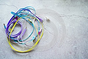 A bunch of colored wires for charging gadgets on a gray concrete background. Copy space