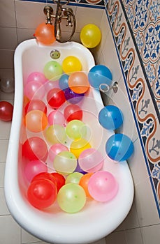 Bunch of colorful balloons in bath tube. Large pile of multicolored inflated balloons