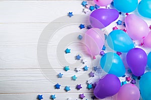 Bunch of colorful party balloons with paper stars on white wooden background