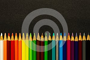 A bunch of colorful pencils lined up over a dark background
