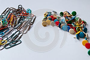 Bunch of colorful thumbtacks and many multi-colored paper-clips organize desktop and home office supplies as well as paperwork