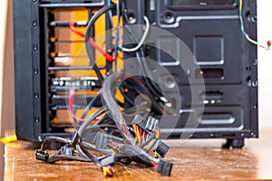 bunch of computer wires sticking out from opened black pc case - close-up with selective focus