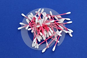 A bunch of cotton buds lie on a blue background.