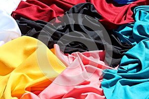 A bunch of different bright, multi-colored fabrics lie in one heap.