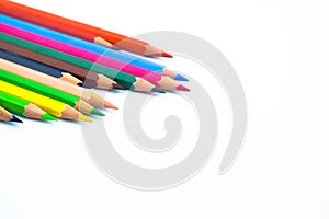 Bunch of different colored wood pencil crayons placed in a pile on a white background