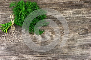 Bunch of dill with tie on wooden background with space for text