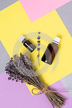 A bunch of dried lavender and oil in a bottle against a background of colorful blocks