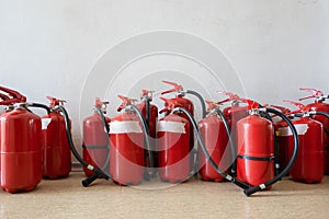 Bunch of expired fire extinguishers on the floor next to the wall. Renewal of extinguishers for businesses