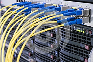 A bunch of fiber-optic Internet wires are connected to the router modules. Yellow telecommunications cable in the server room of