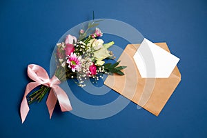 Bunch of flowers kraft paper envelope with blank white letter with copy space lay on blue background