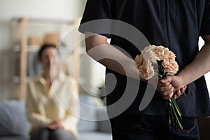 Bunch of flowers in male hands behind back