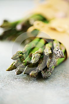 Bunch of fresh asparagus on gray backgrouns. Asparagus on craft paper with packthread. Raw, vegan, vegetarian and clean