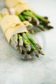 Bunch of fresh asparagus on gray backgrouns. Asparagus on craft paper with packthread. Raw, vegan, vegetarian and clean