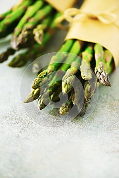 Bunch of fresh asparagus on gray backgrouns. Asparagus on craft paper with packthread. Raw, vegan, vegetarian and clean