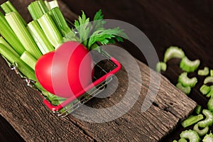 Bunch of fresh celery stalk in shopping basket with leaves and red heart for healthy concept. Food and ingredients of vegetable.