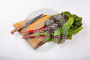 Bunch of fresh chard leaves on cutting board on white background. Top view