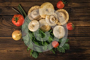 A bunch of fresh dairy wild mushrooms, tomatoes and parsley on a wooden background. Flat lay