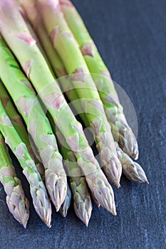 Bunch of fresh green asparagus on  dark slate background, vertical