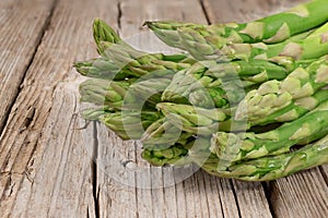 Bunch of fresh green asparagus spears on brown rustic wooden table, macro photo